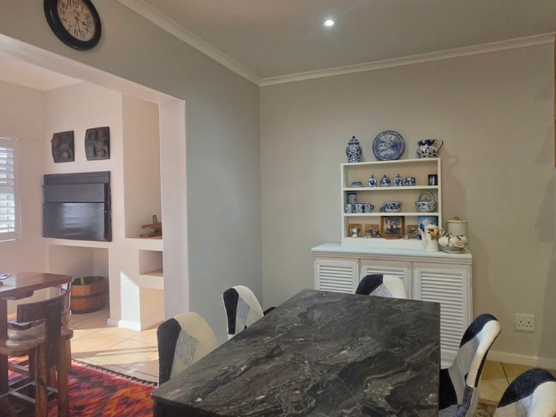 Open-plan living and dining area featuring tiled floors, modern cabinetry, stone countertops, and direct access to an outdoor patio space.