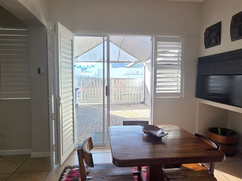 Dining area featuring tiled flooring, plantation shutters, and a built-in wall niche, with direct access to an outdoor paved patio area.