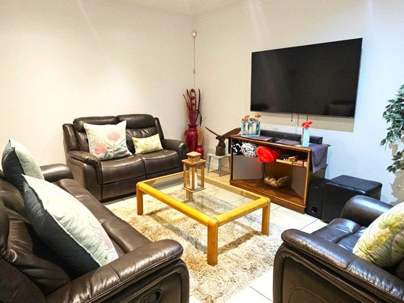 A comfortable living room featuring tiled flooring and window shutters, providing a functional space for relaxation and entertainment.