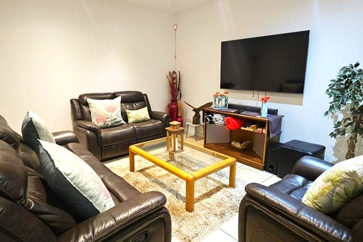 A comfortable living room featuring tiled flooring and window shutters, providing a functional space for relaxation and entertainment.
