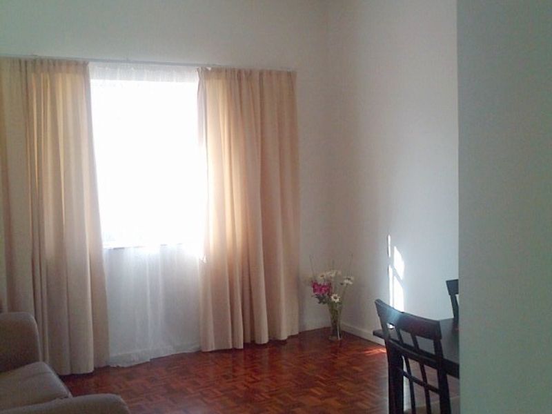 A living room area featuring classic parquet flooring and natural light through a window with curtains.