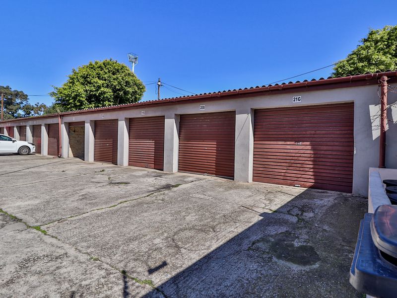 A row of numbered garage units featuring roller shutter doors and a shared concrete driveway area.