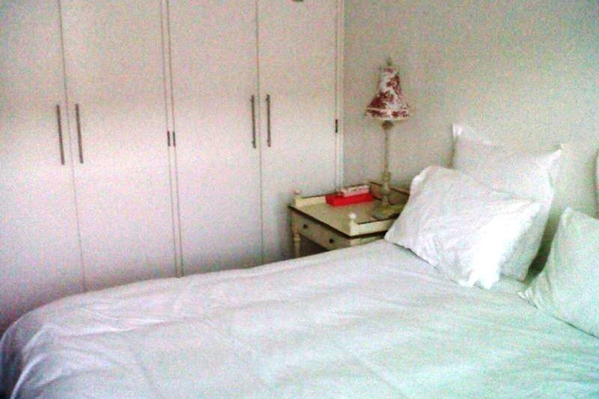 A bedroom featuring white built-in cupboards providing ample storage space.