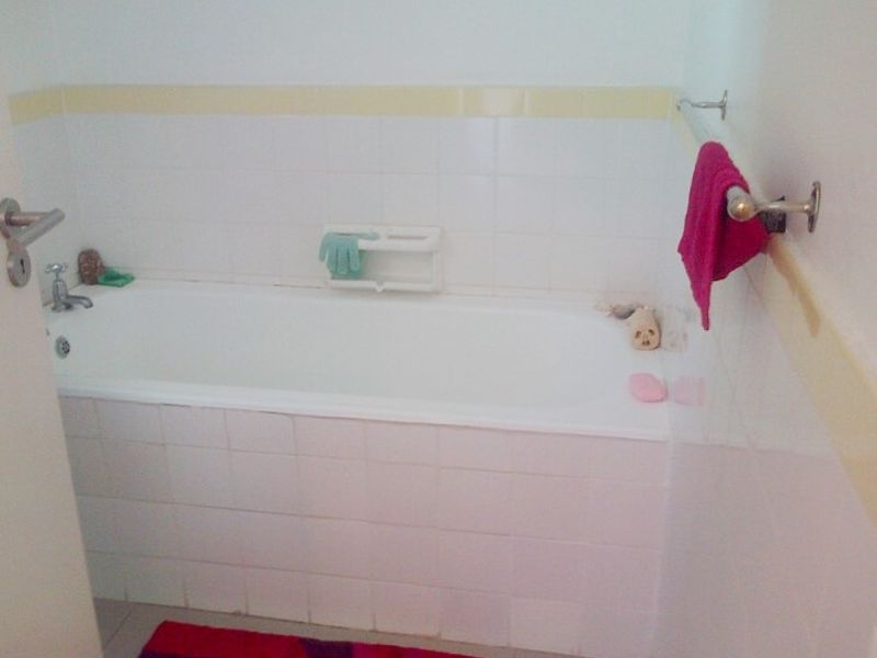 A functional bathroom featuring a standard bathtub with white wall tiling and a chrome towel rail.