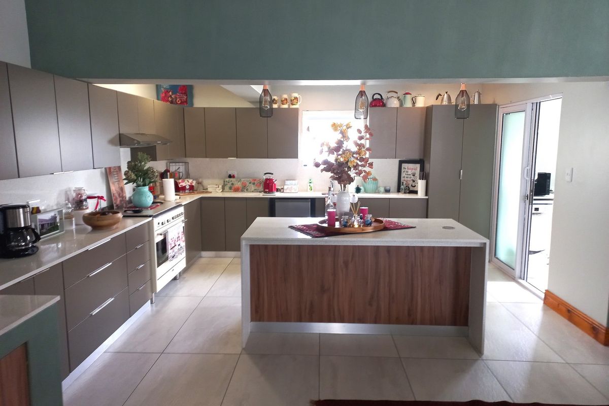 Modern kitchen featuring sleek cabinetry, stone countertops, a central island, and integrated appliances, with direct access to an outdoor area.