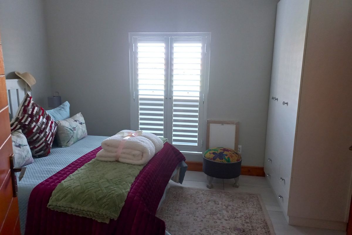 A bedroom featuring built-in cabinetry and white plantation shutters on the window, providing a functional and neutral living space.
