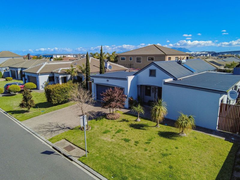 Aerial view of a residential property featuring a paved driveway, garage, and well-maintained lawn in a suburban estate setting.