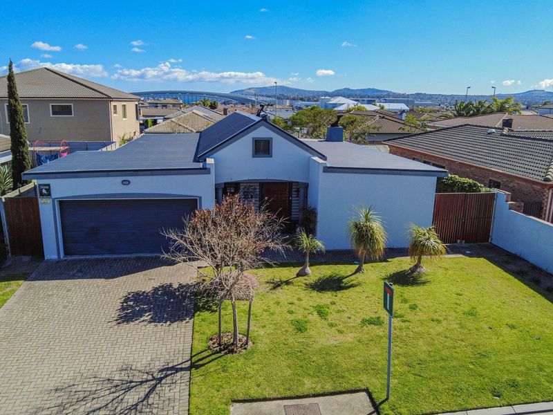 Aerial view of a residential property featuring a paved driveway, double garage, and a well-maintained front lawn in a suburban neighborhood.