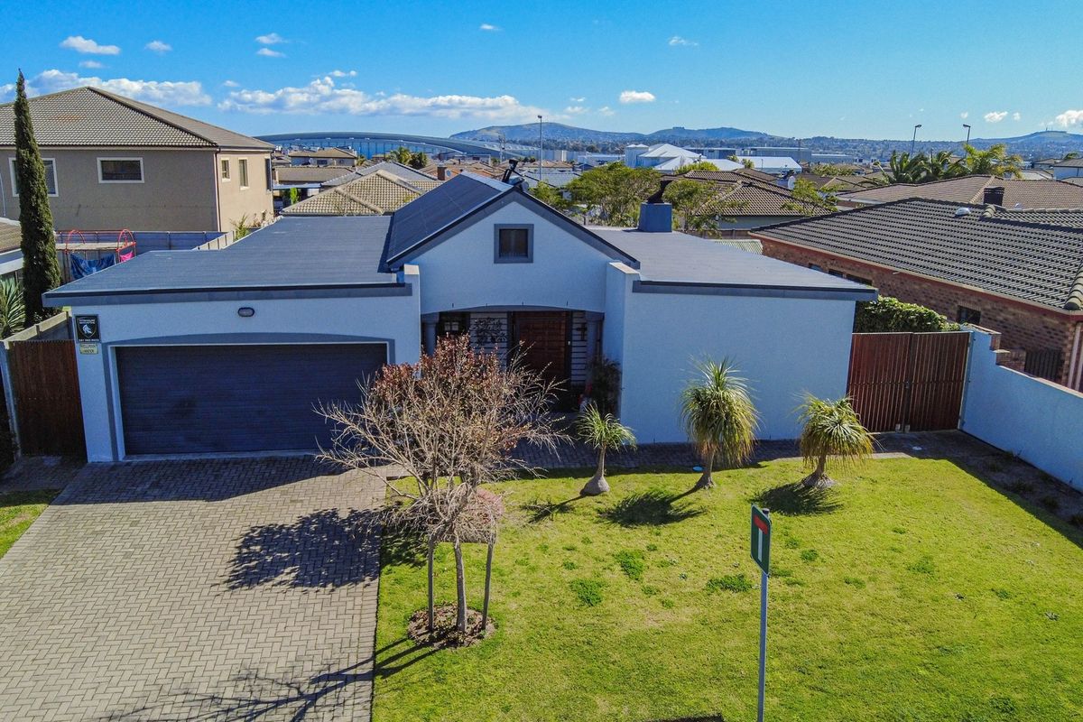 Aerial view of a residential property featuring a paved driveway, double garage, and a well-maintained front lawn in a suburban neighborhood.