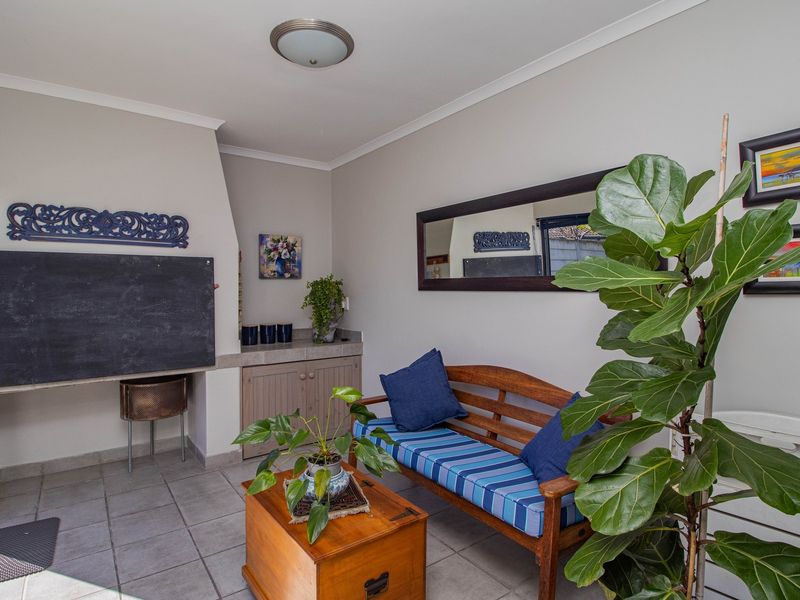 A covered patio area featuring a built-in braai, tiled flooring, and built-in storage cabinetry, suitable for outdoor entertaining.