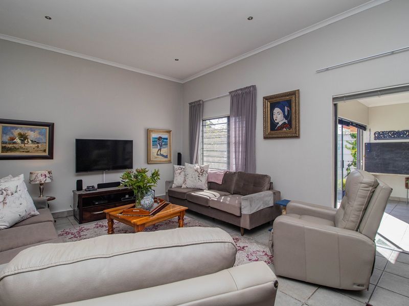 A well-maintained living room featuring neutral walls, recessed downlighting, and tiled flooring, with direct access to an outdoor patio area through sliding glass doors.