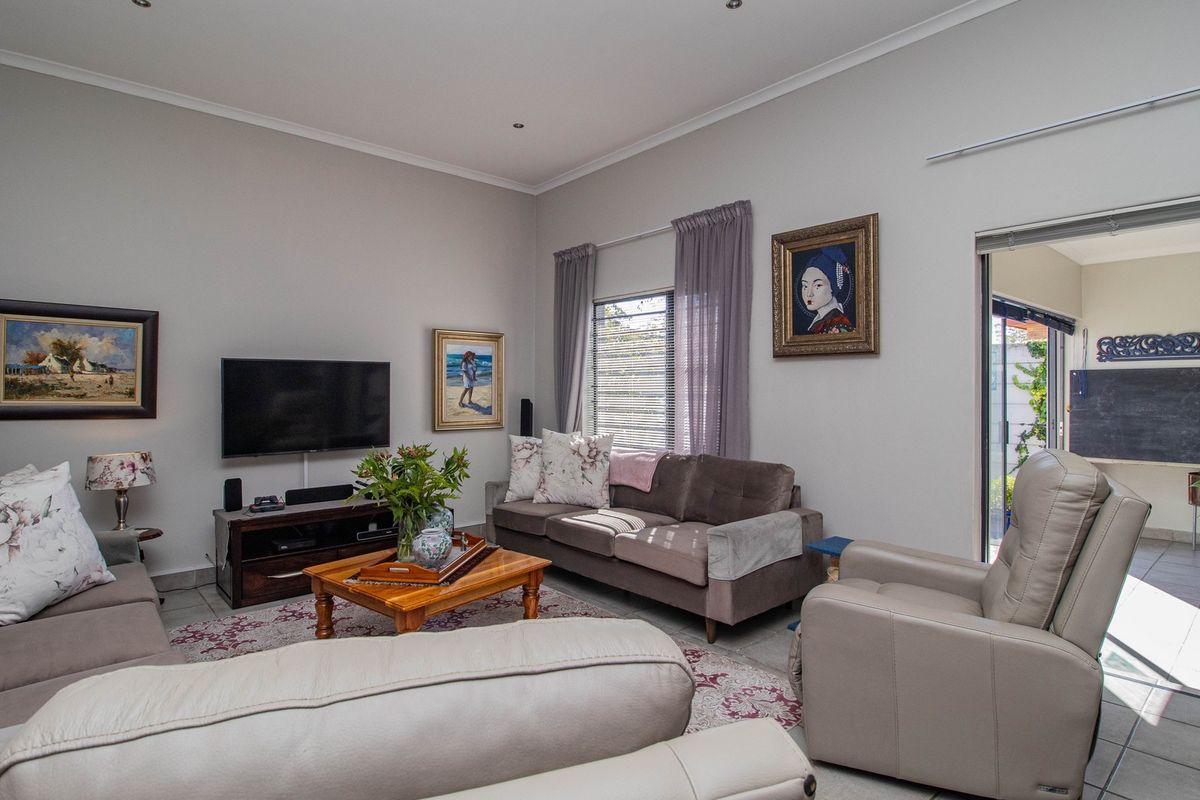 A well-maintained living room featuring neutral walls, recessed downlighting, and tiled flooring, with direct access to an outdoor patio area through sliding glass doors.