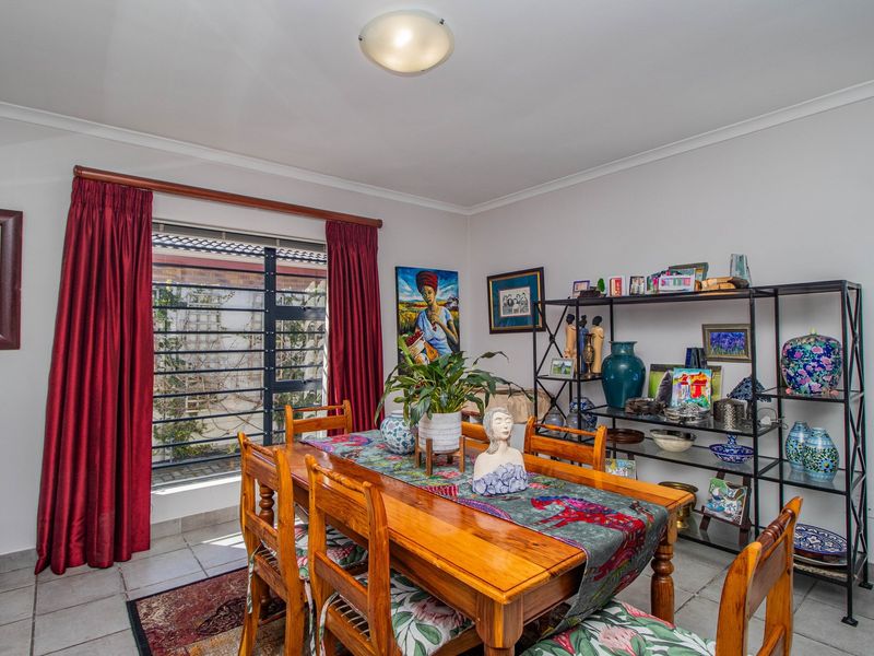 A functional dining room featuring tiled flooring and a window fitted with security bars, providing a bright and practical space for meals.