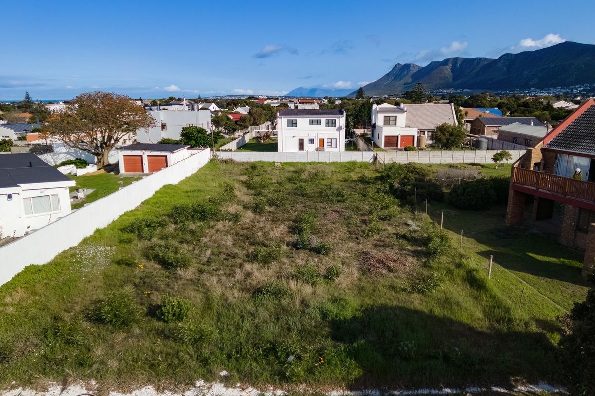 Aerial view of a vacant residential plot situated in a developed neighborhood with mountain and coastal views.