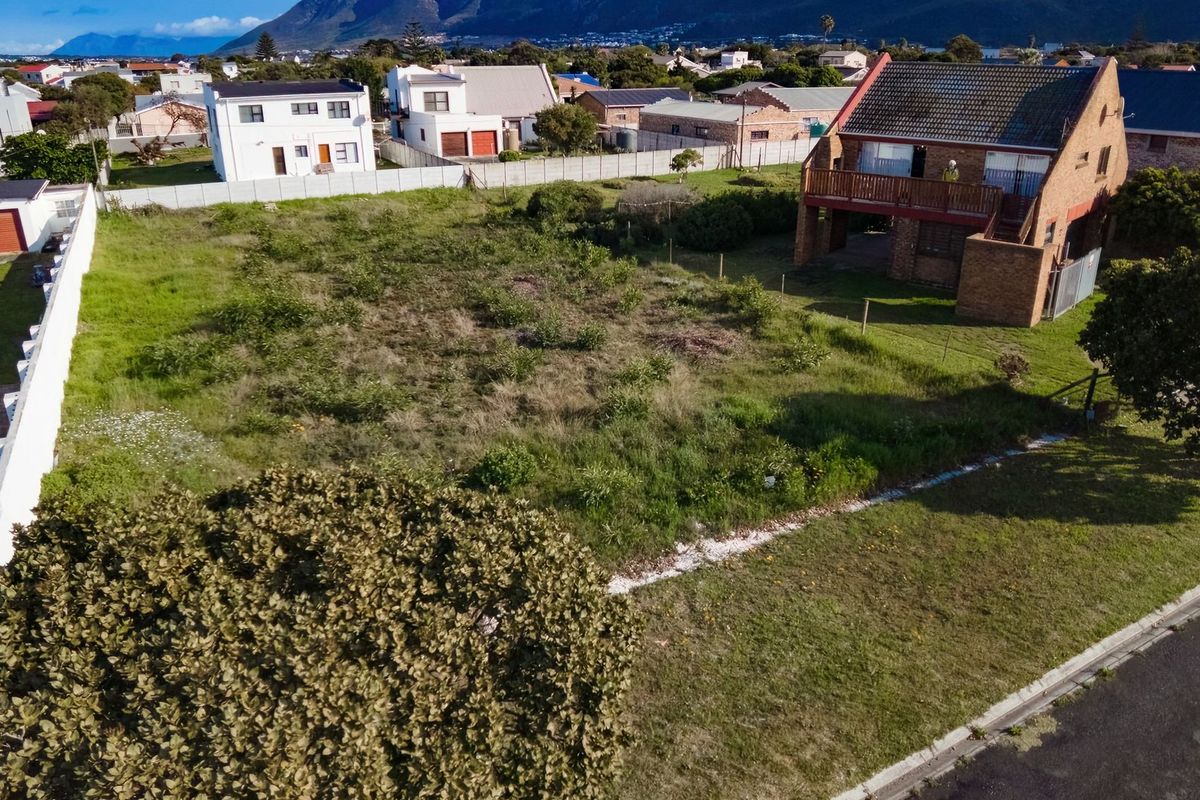 An aerial view of a vacant residential plot featuring grassed land and perimeter fencing in a developed neighborhood.