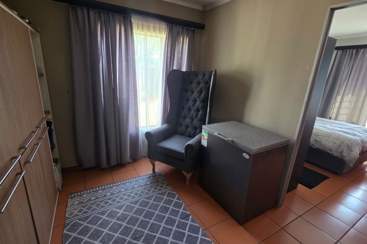 A bedroom area featuring tiled flooring, built-in cabinetry, and direct access to an adjoining sleeping space with natural light.