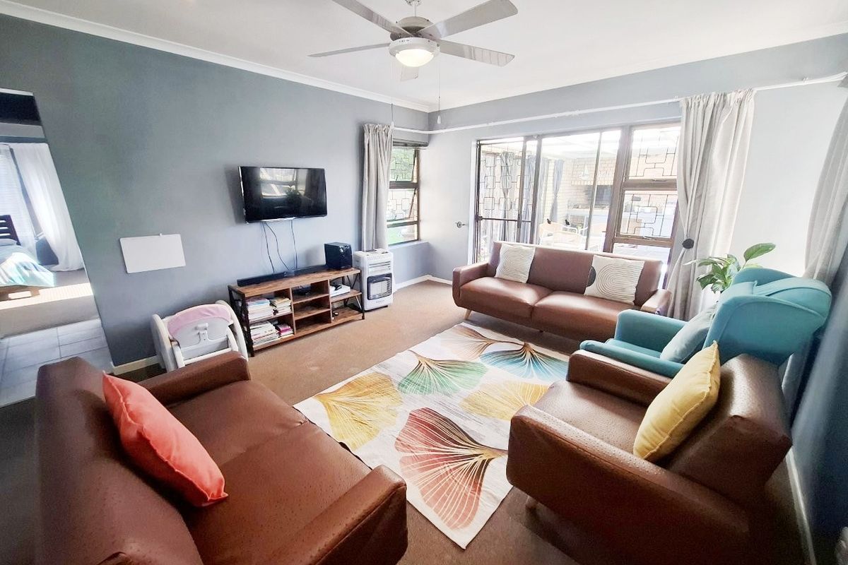 A comfortable living room featuring a ceiling fan, recessed lighting, and large sliding glass doors that provide access to the outdoor area.