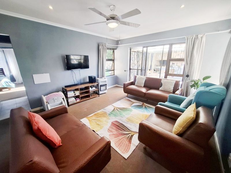 A comfortable living room featuring a ceiling fan, recessed lighting, and large sliding glass doors that provide access to the outdoor area.