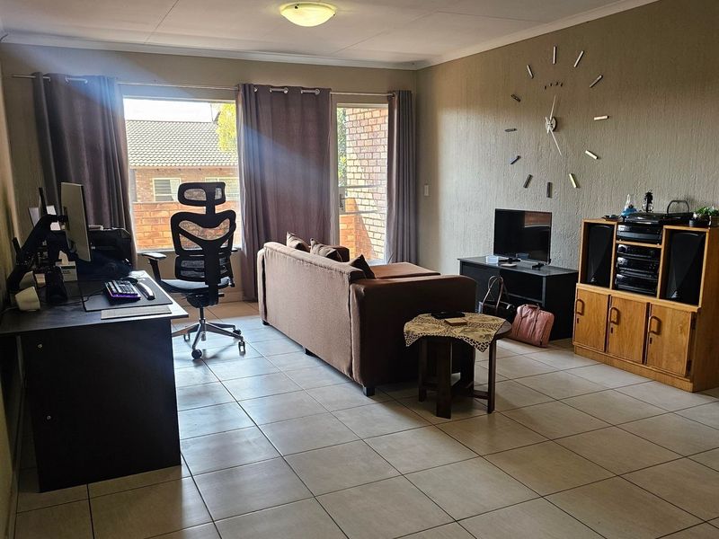 A spacious living room featuring neutral tiled flooring, a coved ceiling, and a sliding glass door providing access to the exterior.