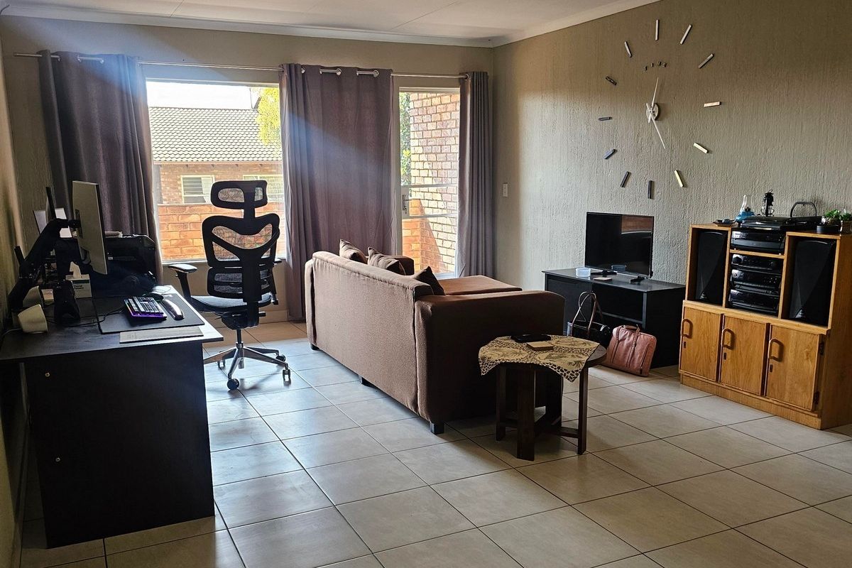 A spacious living room featuring neutral tiled flooring, a coved ceiling, and a sliding glass door providing access to the exterior.