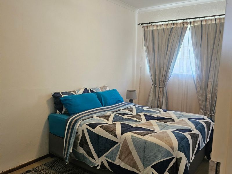 A standard bedroom featuring a window with installed curtain rods and neutral wall finishes.