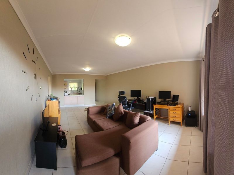 An open-plan living area featuring tiled flooring, neutral walls, and a convenient pass-through window connecting to the kitchen space.