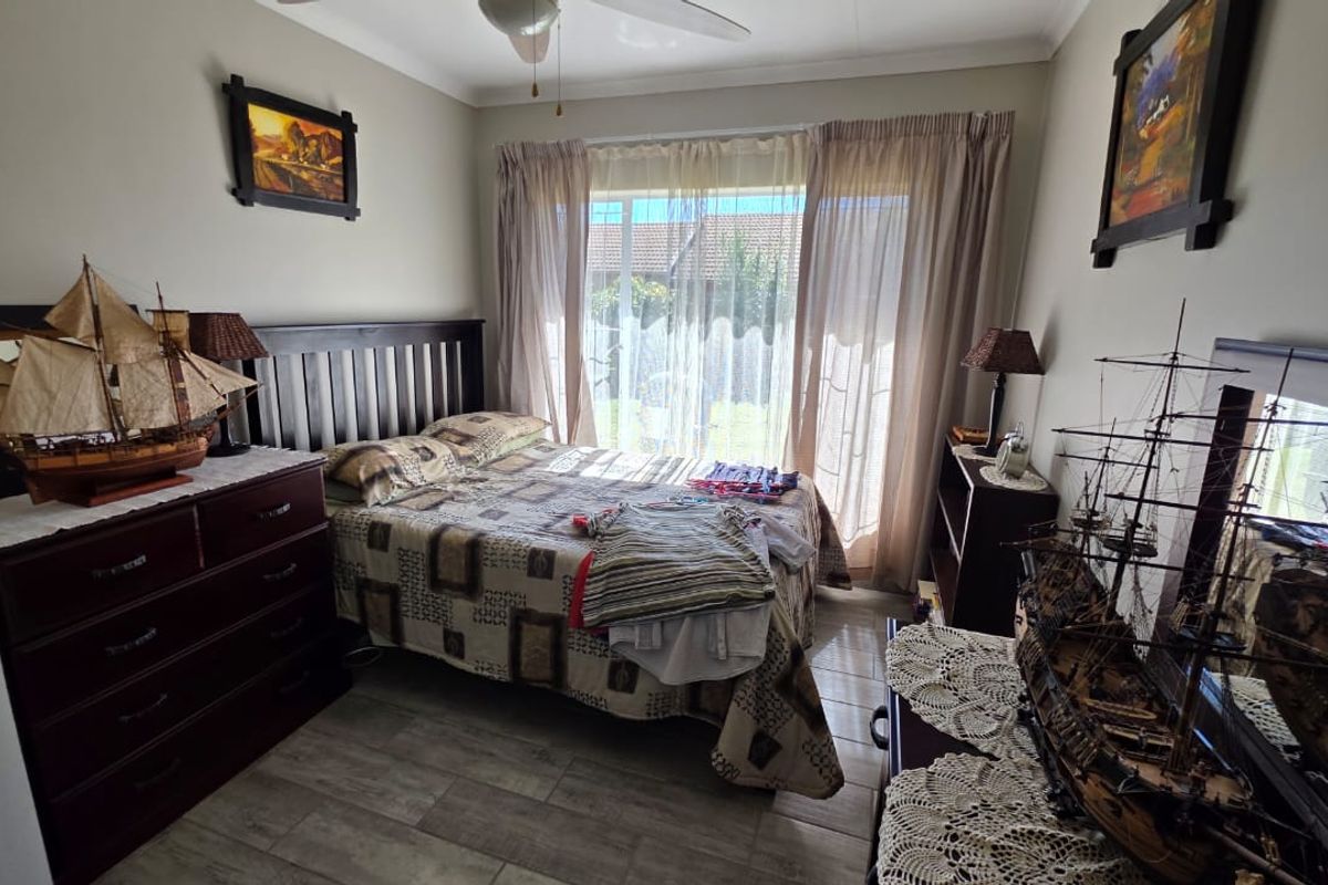 A bedroom featuring tiled flooring, a ceiling fan, and large sliding glass doors providing natural light and access to the exterior.