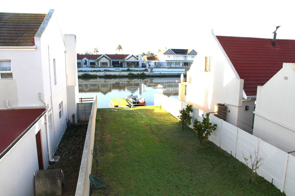A view of the rear garden leading down to the canal, featuring a private jetty and water access.
