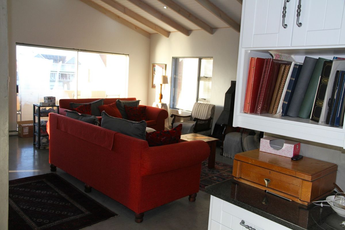Spacious living area featuring vaulted ceilings with exposed beams, polished concrete flooring, and large sliding glass doors providing ample natural light.
