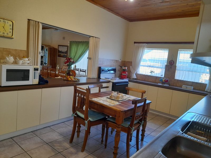 A functional kitchen featuring built-in cabinetry, laminate countertops, a double stainless steel sink, and a pass-through window connecting to the adjacent living area.