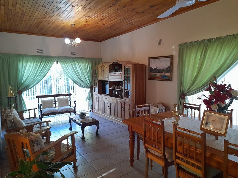 Open plan living and dining area featuring a timber tongue and groove ceiling, ceramic tiled flooring, and sliding glass doors leading to the exterior.