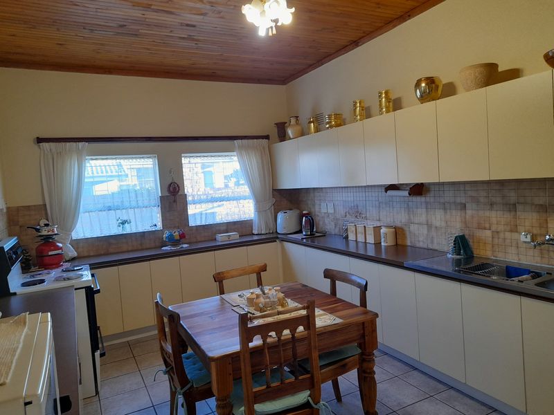 A functional kitchen featuring timber ceilings, tiled splashbacks, laminate countertops, and ample built-in cabinetry with a dedicated dining area.