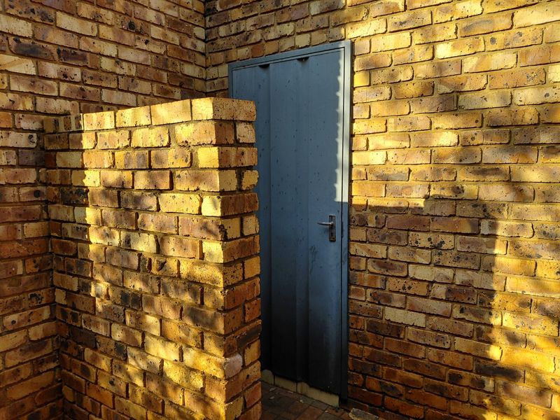 A view of a face brick exterior wall featuring a metal door, typical of a rear utility or service entrance area.