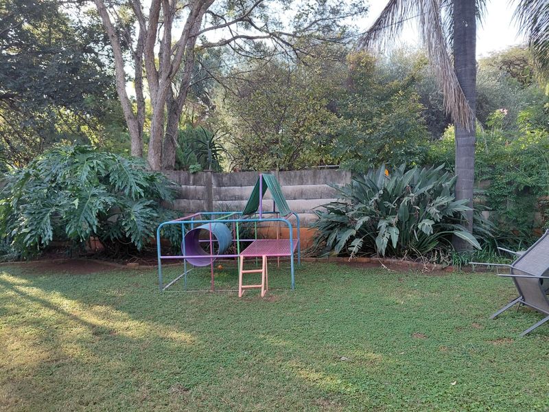 A private garden area featuring a well-maintained lawn, mature trees, and a concrete block boundary wall providing privacy.