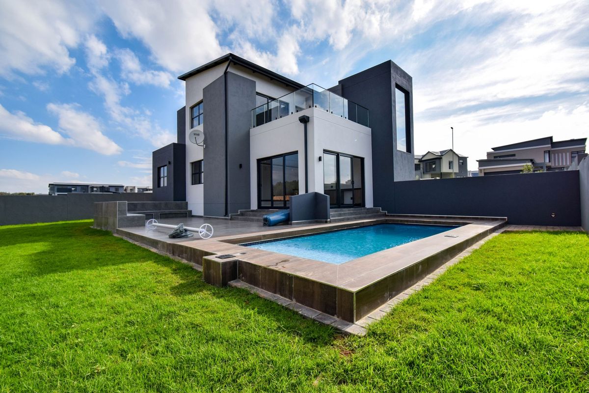 Modern double-story residence featuring a rear patio, swimming pool, and landscaped garden, showcasing contemporary architectural design and clean exterior finishes.