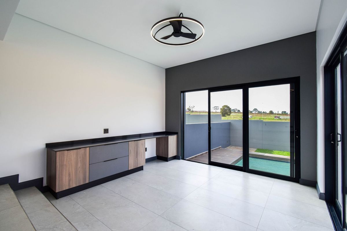 Modern living area featuring built-in cabinetry, large sliding glass doors, and a contemporary ceiling fan, with direct access to a private pool area.