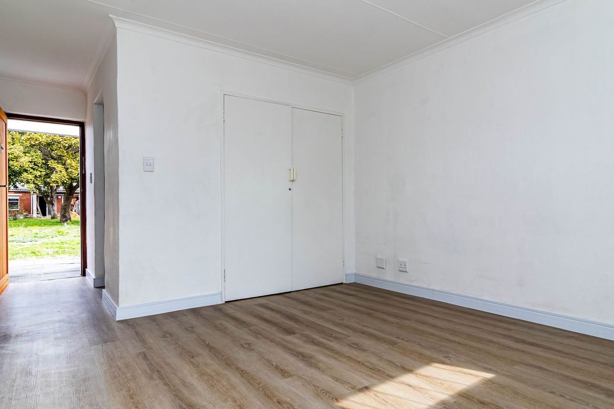 An empty bedroom featuring laminate flooring, a built-in cupboard, and direct access to an outdoor area.