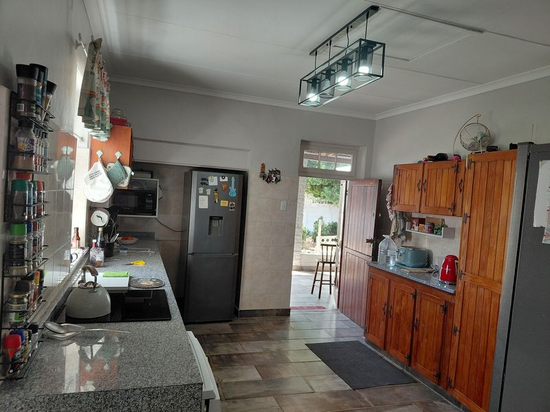 Functional kitchen featuring granite countertops, wooden cabinetry, and tiled flooring with direct access to an outdoor patio area.