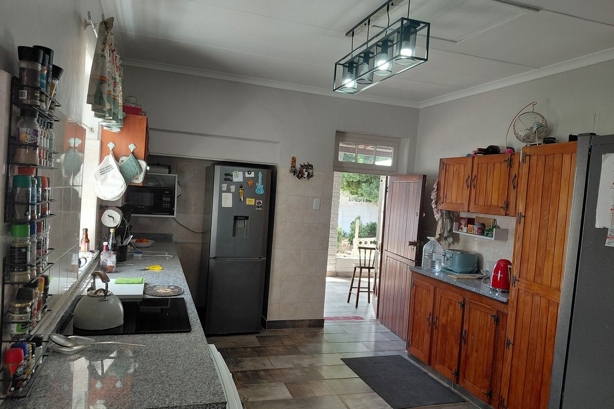 Functional kitchen featuring granite countertops, wooden cabinetry, and tiled flooring with direct access to an outdoor patio area.