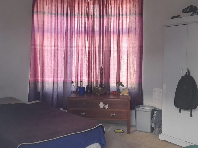 A bedroom featuring a large window with curtains, providing natural light to the space.