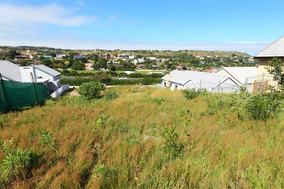 A vacant residential plot featuring a gentle slope, natural vegetation, and surrounding neighborhood views, ideal for future development.