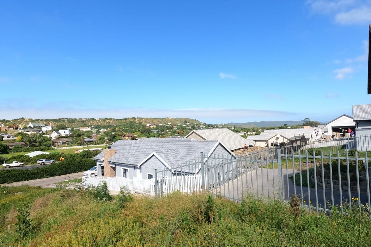 Elevated view of a residential area featuring modern homes with tiled roofs and secure perimeter fencing, set against a scenic landscape.