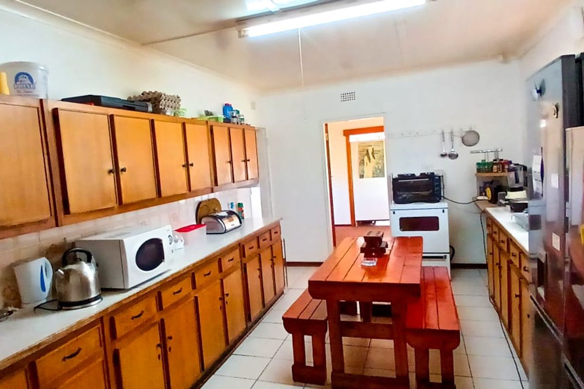 A functional kitchen featuring extensive wooden cabinetry, tiled flooring, and a central dining area, providing a practical space for meal preparation and casual dining.