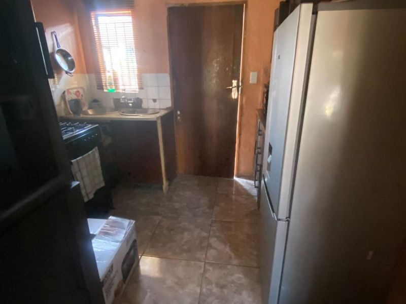 A compact kitchen featuring tiled flooring, basic cabinetry, and a functional layout with direct access to an exterior door.