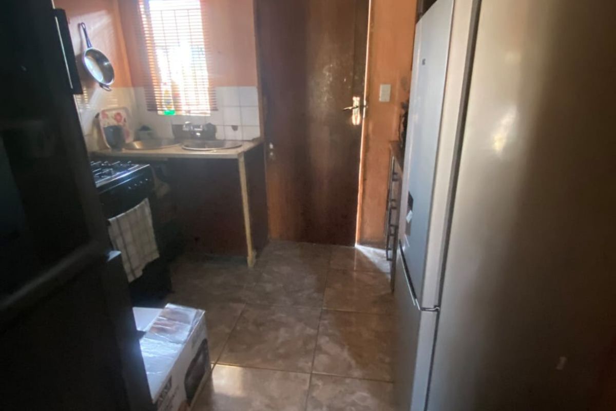A compact kitchen featuring tiled flooring, basic cabinetry, and a functional layout with direct access to an exterior door.