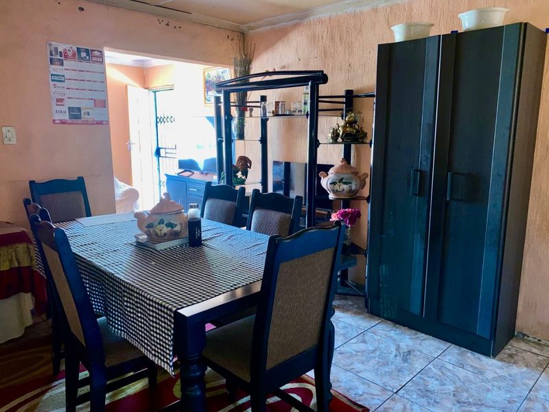 A dining area featuring tiled flooring and textured walls, providing a functional space for family meals with direct access to the adjacent room.