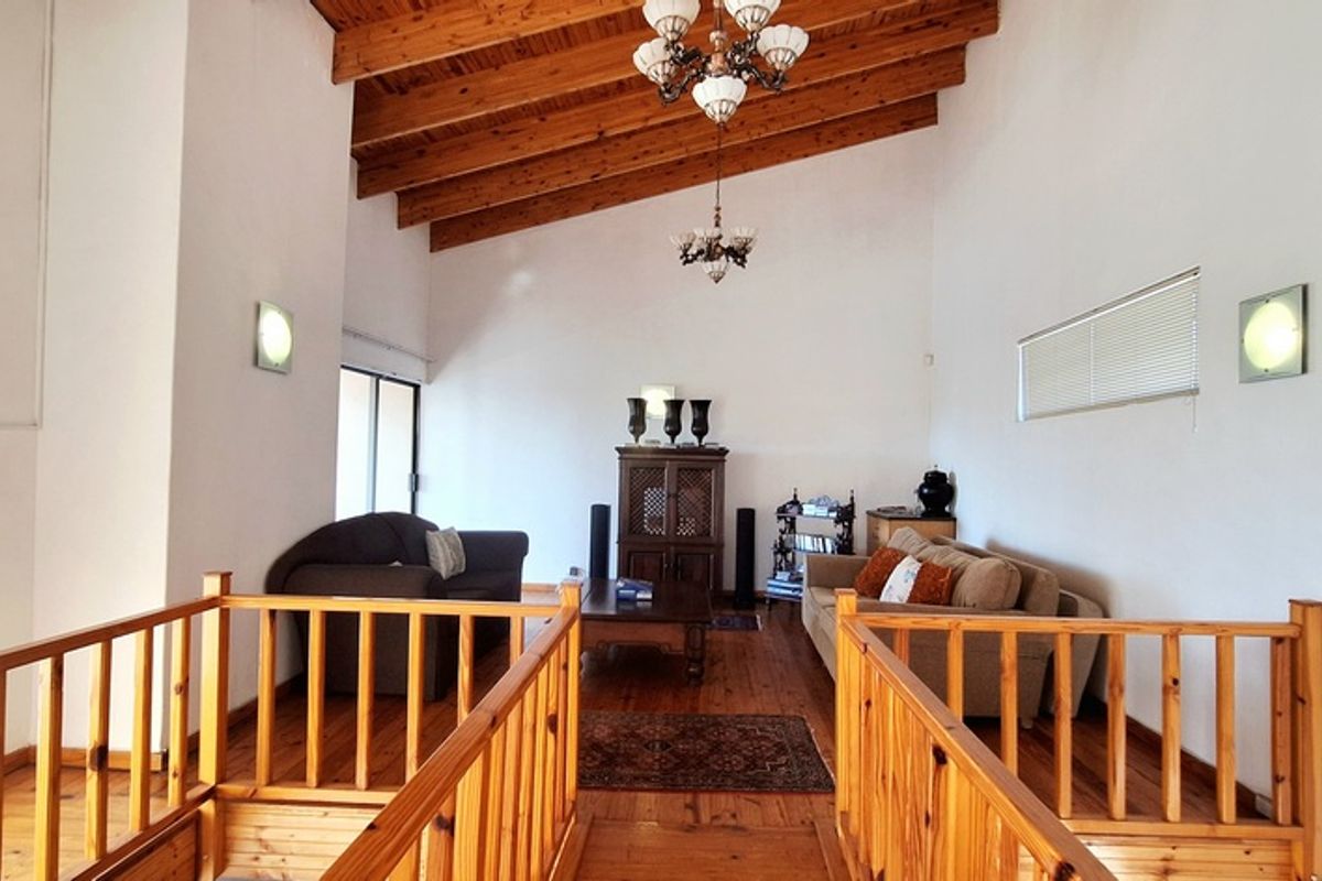 Spacious living area featuring high vaulted timber ceilings, exposed wooden beams, and warm timber flooring, creating a rustic and inviting atmosphere.