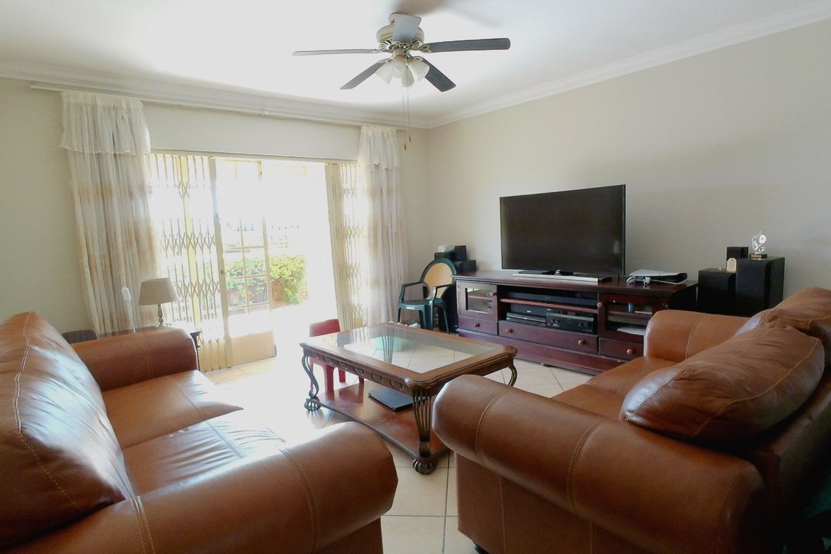 A comfortable living room featuring tiled flooring, a ceiling fan, and sliding glass doors that provide access to the outdoor area.