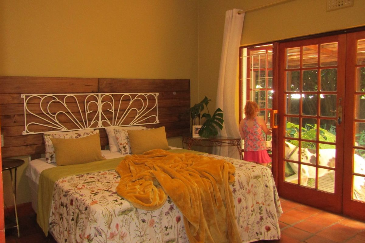 A bedroom featuring terracotta tile flooring, timber wall paneling, and timber-framed glass sliding doors providing direct access to the outdoor area.