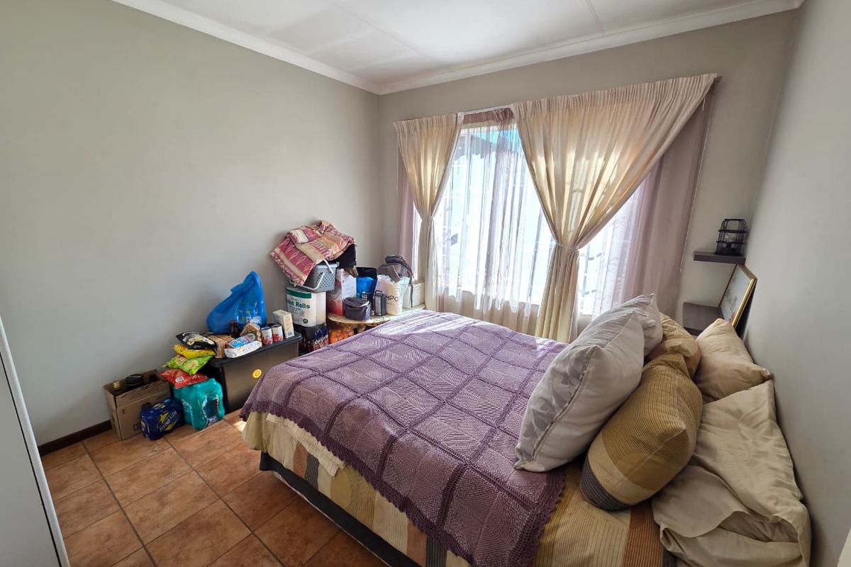 A bedroom featuring tiled flooring and a large window with curtain tracks, providing natural light to the space.